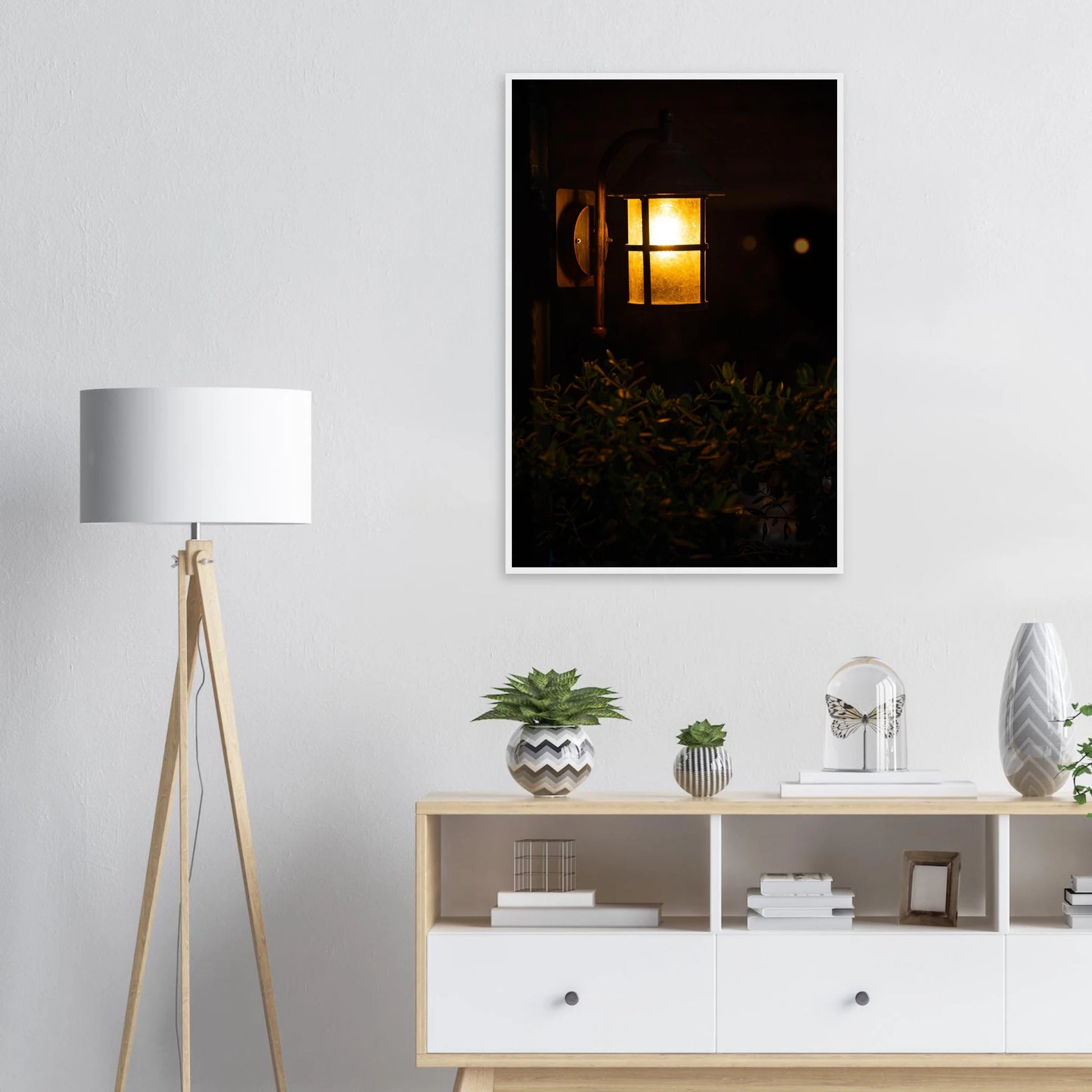 Glowing vintage lantern mounted on a wooden pole in front of a bush at night on wooden framed wall art on the wall in the Livingroom