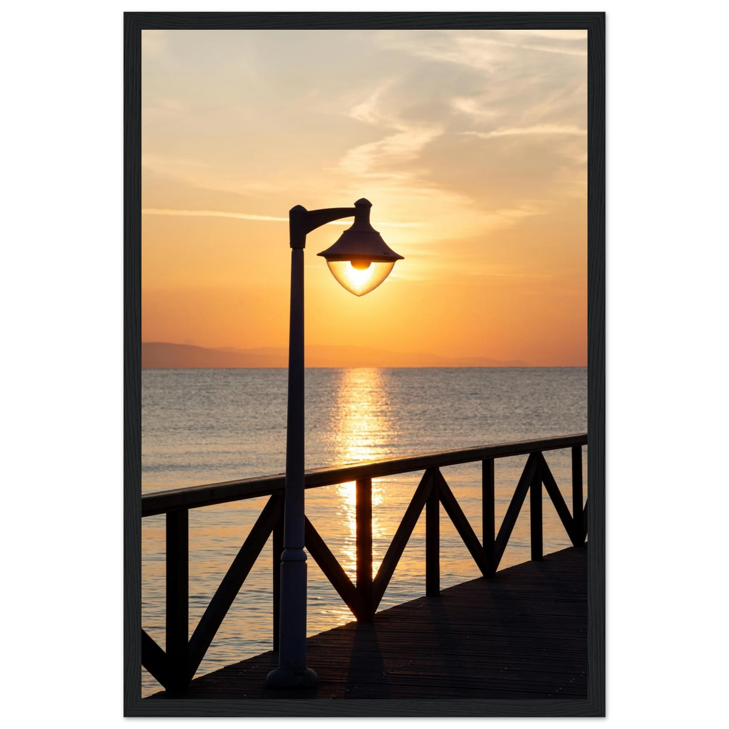 Wooden framed wall art of a sunset over the sea with a street lamp on the pier