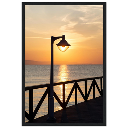 Wooden framed wall art of a sunset over the sea with a street lamp on the pier