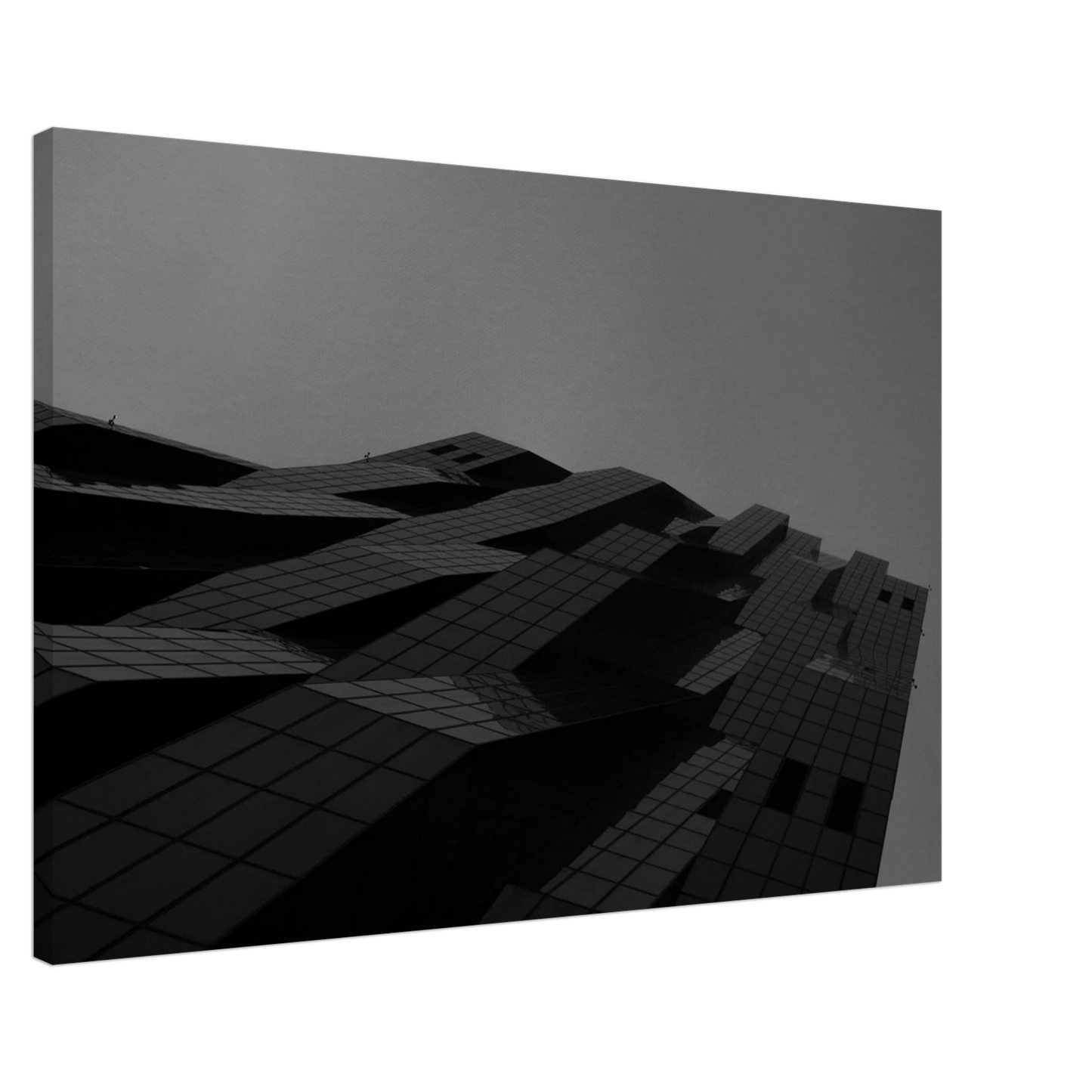 Black and white low angle view of a modern skyscraper with bold geometric lines and dark textured facade on Canvas Print wall art