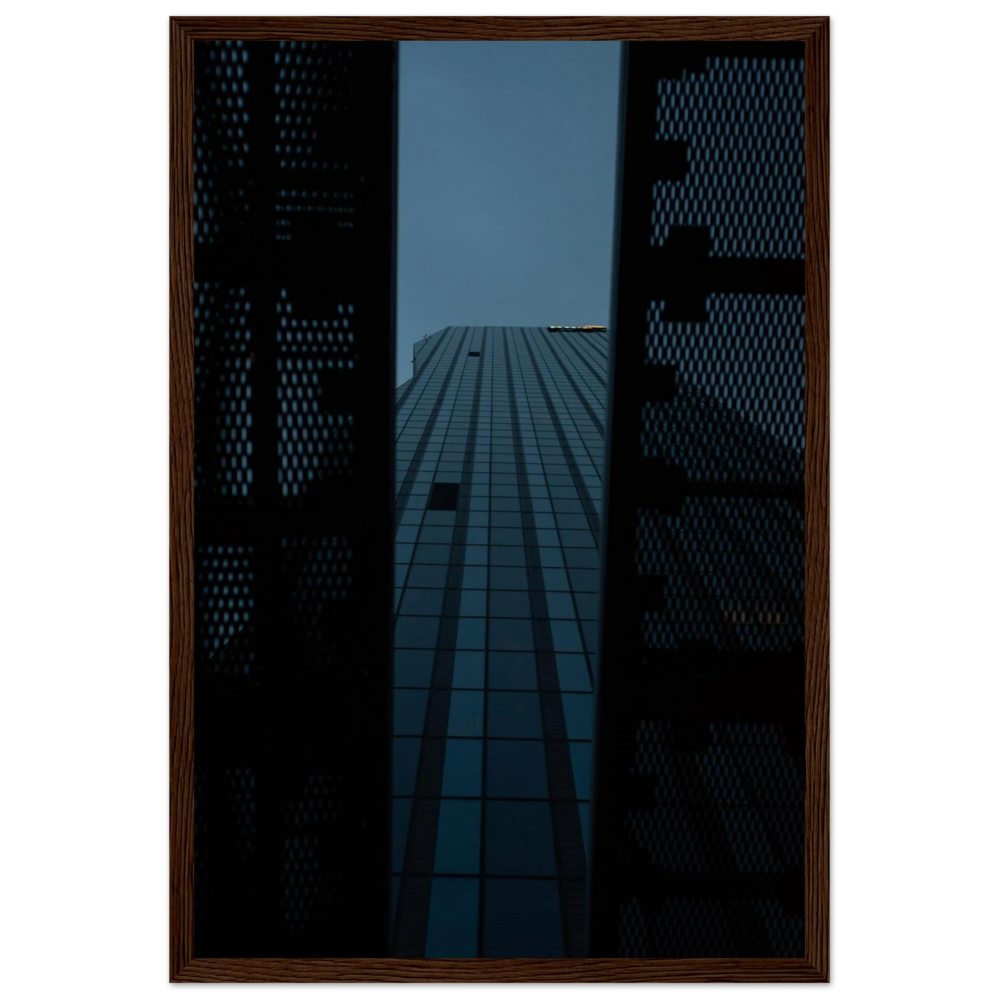 Low angle view looking up at a tall glass skyscraper framed between two metal structural elements on wooden framed wall art