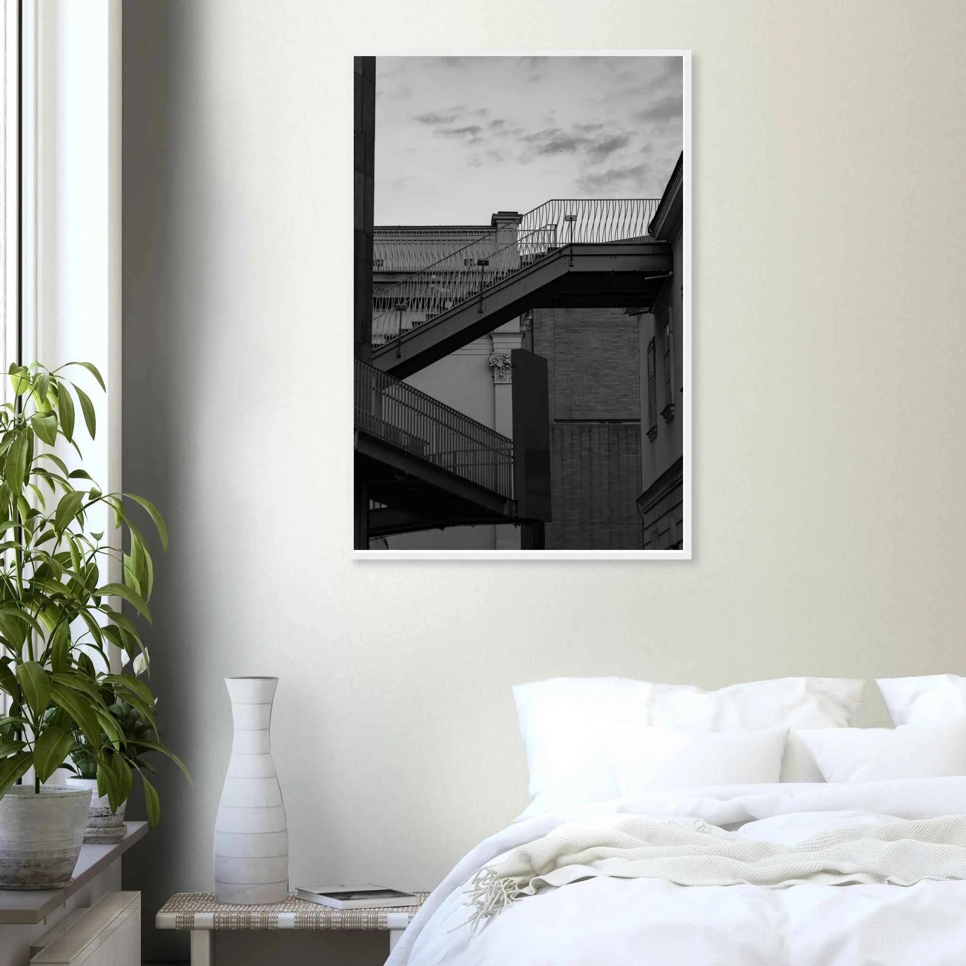 Black and white photo on a wooden frame wall art of an outdoor staircase connecting two buildings under a dramatic cloudy sky on the wall in the Bedroom