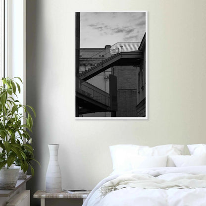 Black and white photo on a wooden frame wall art of an outdoor staircase connecting two buildings under a dramatic cloudy sky on the wall in the Bedroom