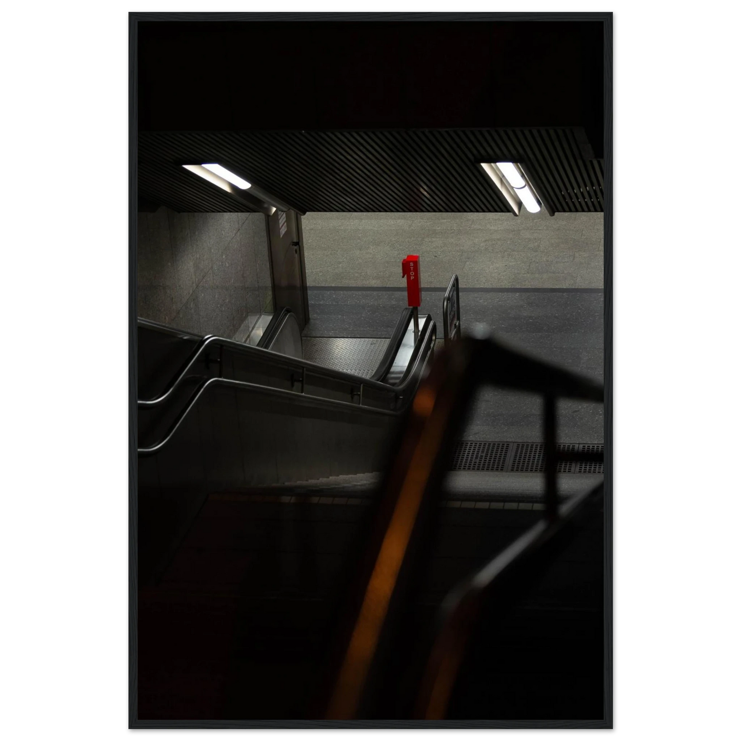 Nighttime view of a metro station entrance with illuminated signs and dark urban surroundings on wooden framed wall art