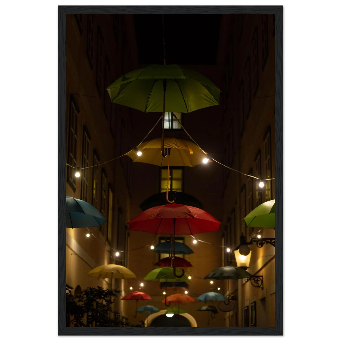 Nighttime street scene with colorful illuminated umbrellas hanging as decoration above a vibrant outdoor area on a wooden frame wall art