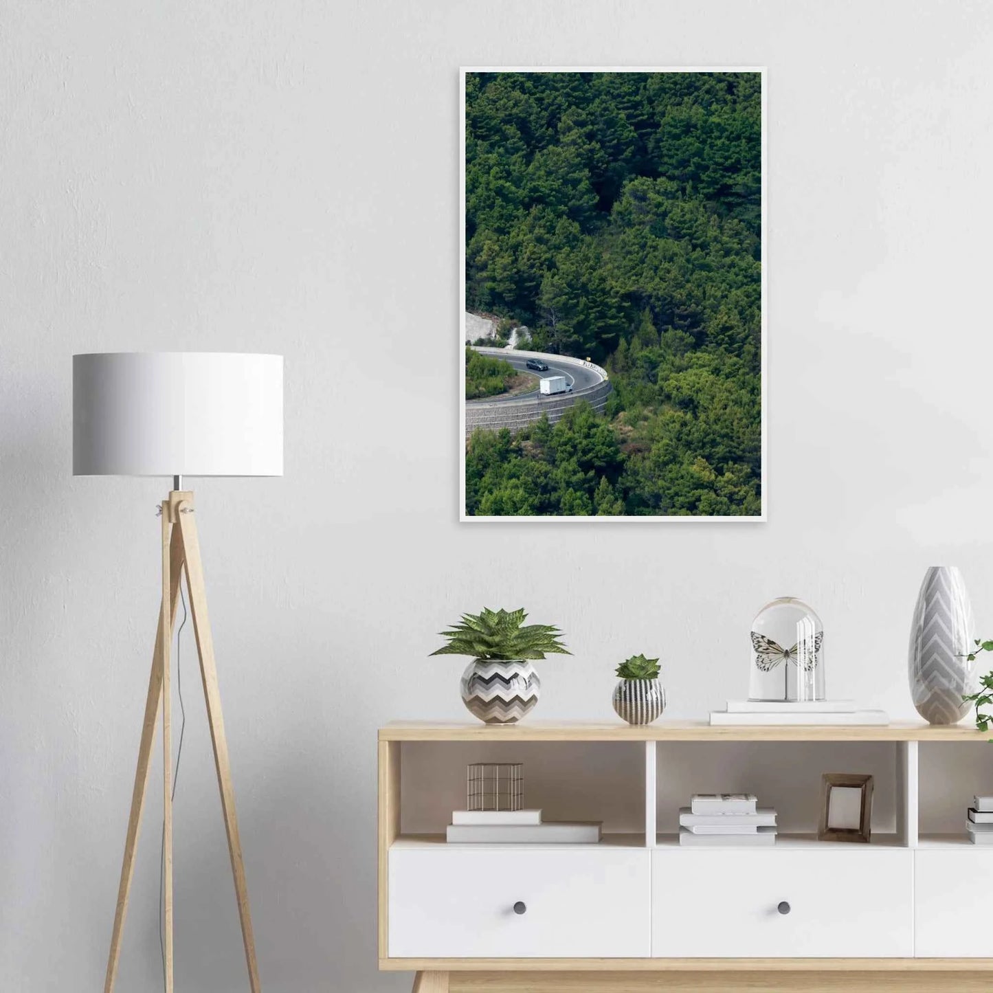 Aerial view of a winding road curve with cars surrounded by lush green forest landscape on wooden framed wall art on the wall in the Livingroom