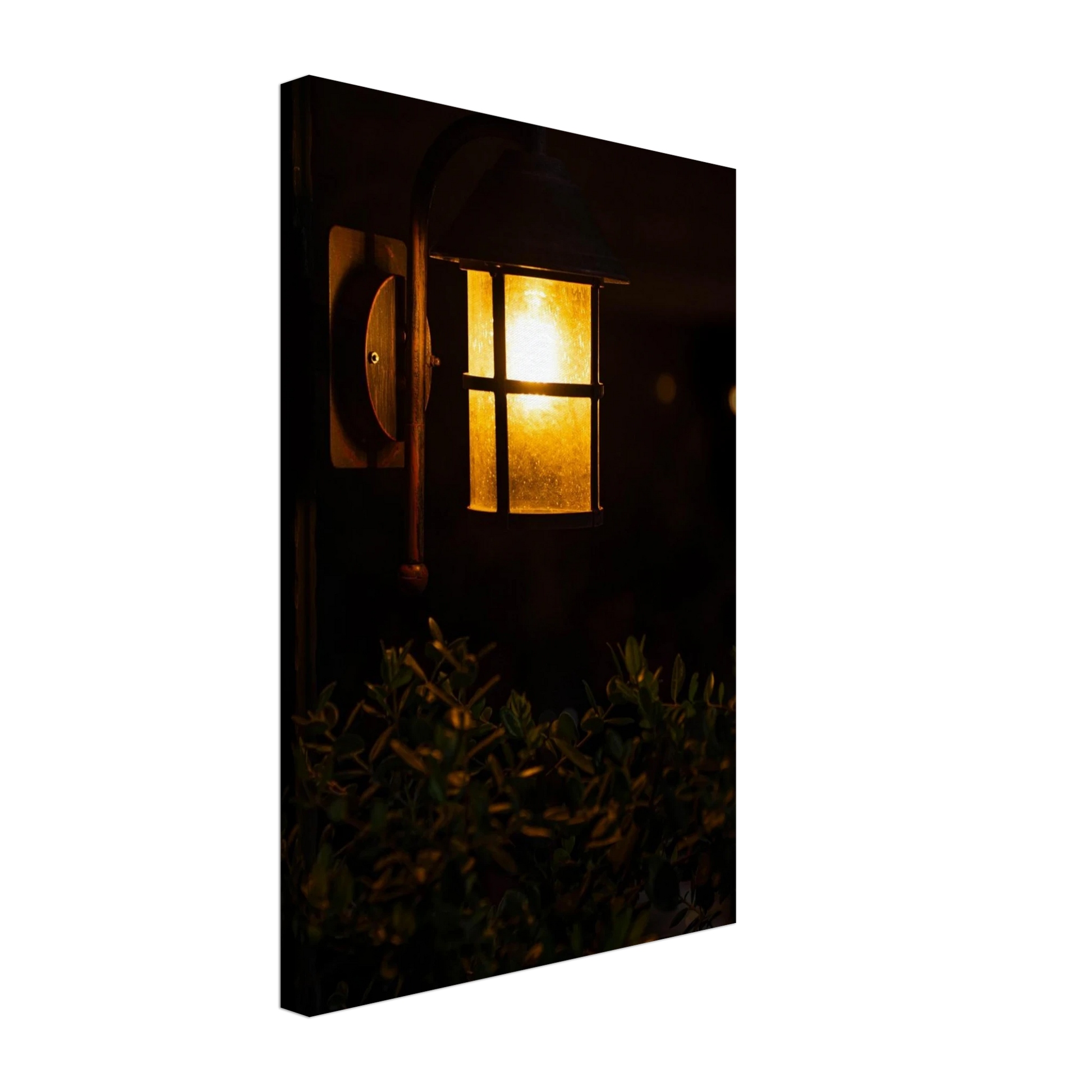Glowing vintage lantern mounted on a wooden pole in front of a bush at night on Canvas Print wall art