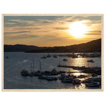 Wooden framed wall art of small boats anchored in a seaside port during Sunset at the harbor