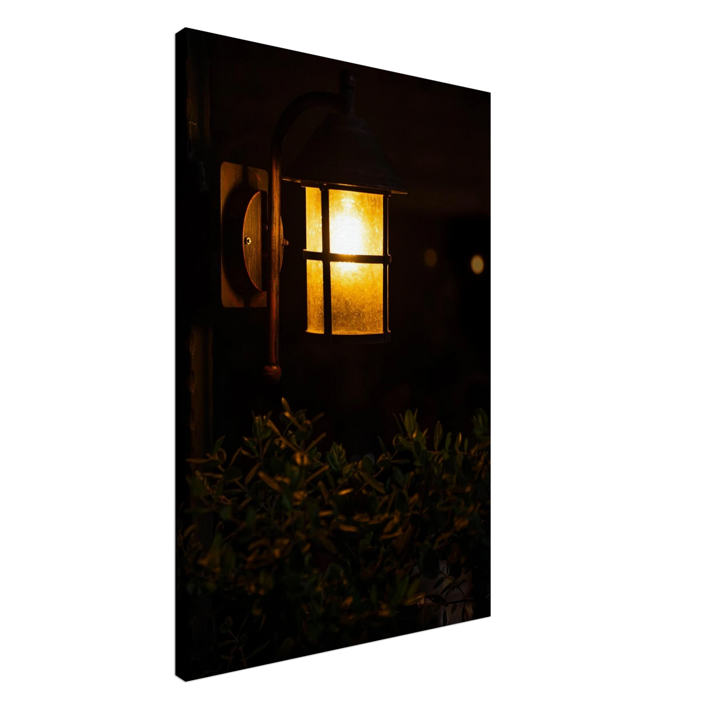 Glowing vintage lantern mounted on a wooden pole in front of a bush at night on Canvas Print wall art