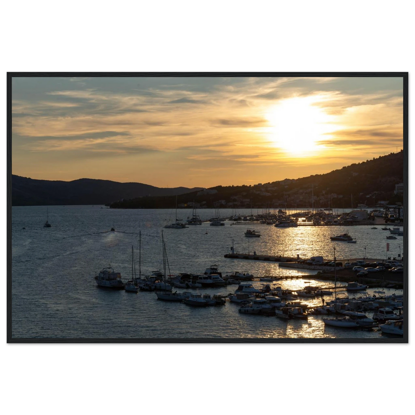 Wooden framed wall art of small boats anchored in a seaside port during Sunset at the harbor