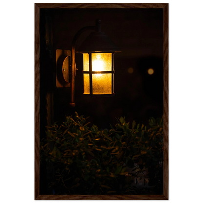 Glowing vintage lantern mounted on a wooden pole in front of a bush at night on wooden framed wall art