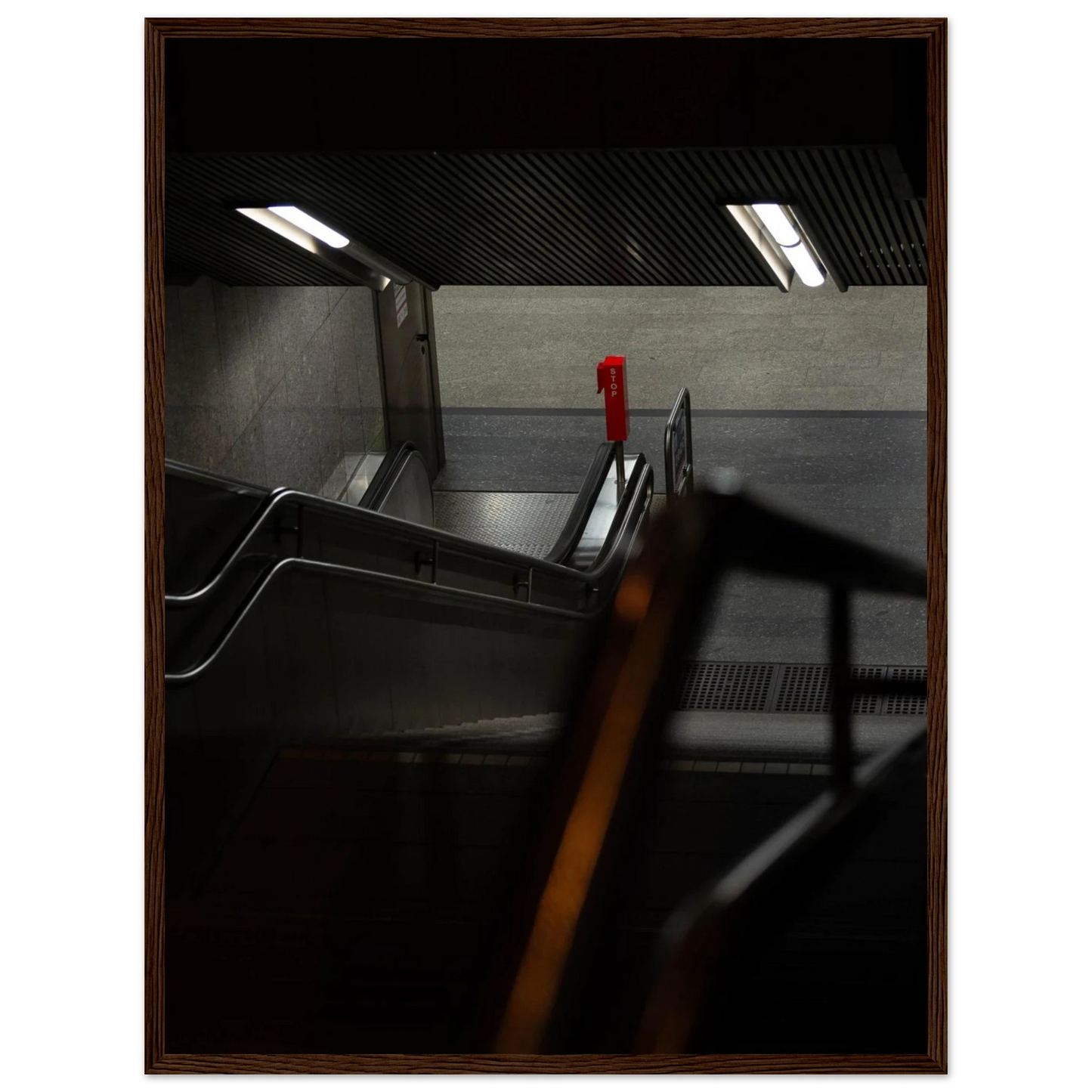 Nighttime view of a metro station entrance with illuminated signs and dark urban surroundings on wooden framed wall art