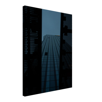 Low angle view looking up at a tall glass skyscraper framed between two metal structural elements on Canvas Print wall art