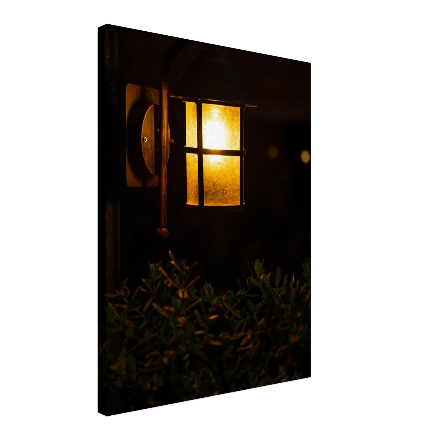 Glowing vintage lantern mounted on a wooden pole in front of a bush at night on Canvas Print wall art