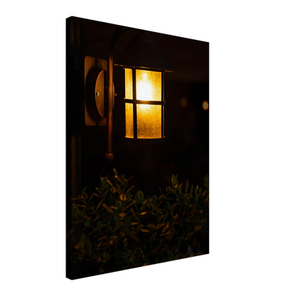 Glowing vintage lantern mounted on a wooden pole in front of a bush at night on Canvas Print wall art