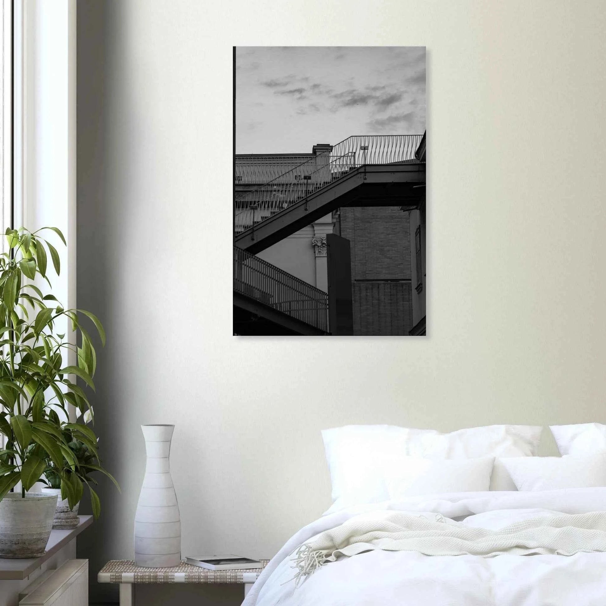Black and white photo on a Canvas print wall art of an outdoor staircase connecting two buildings under a dramatic cloudy sky on the wall in the Bedroom