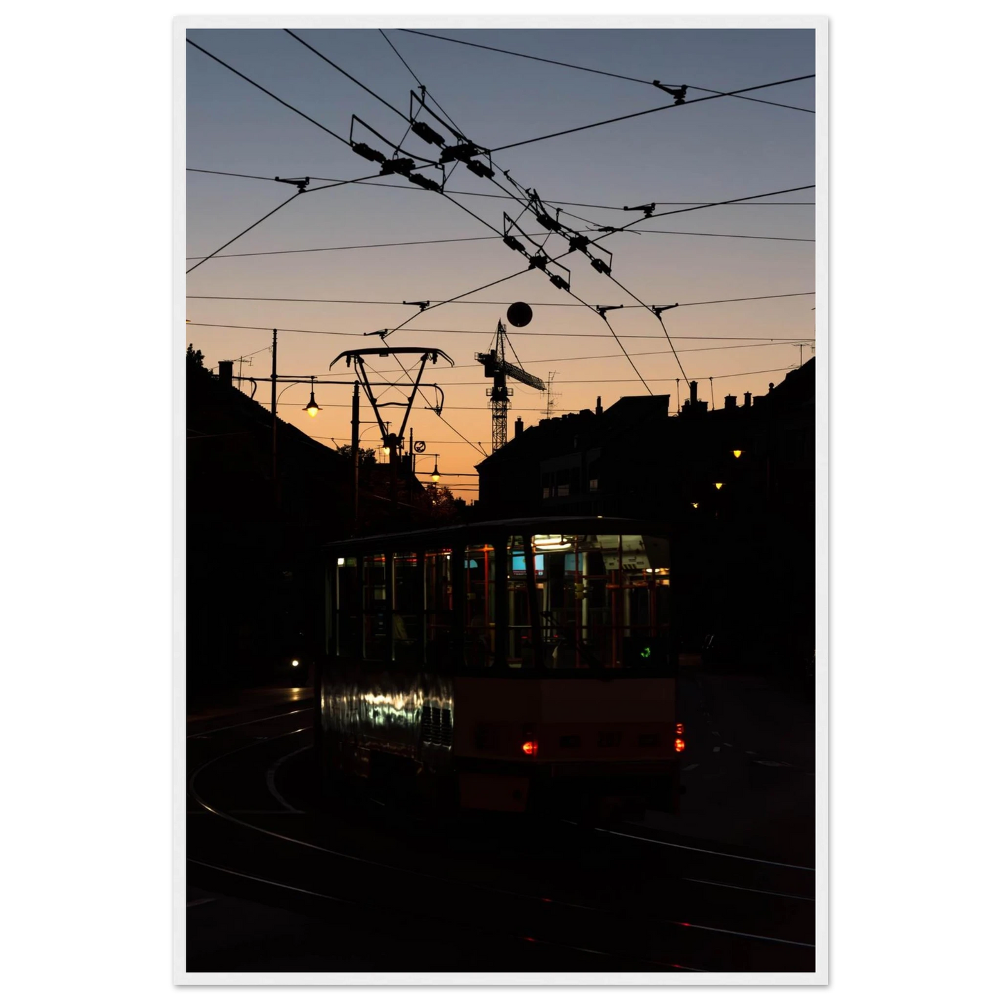 Wooden framed wall art featuring a tram the Nightline driving between houses under power lines during a golden sunset