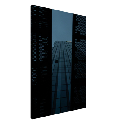 Low angle view looking up at a tall glass skyscraper framed between two metal structural elements on Canvas Print wall art