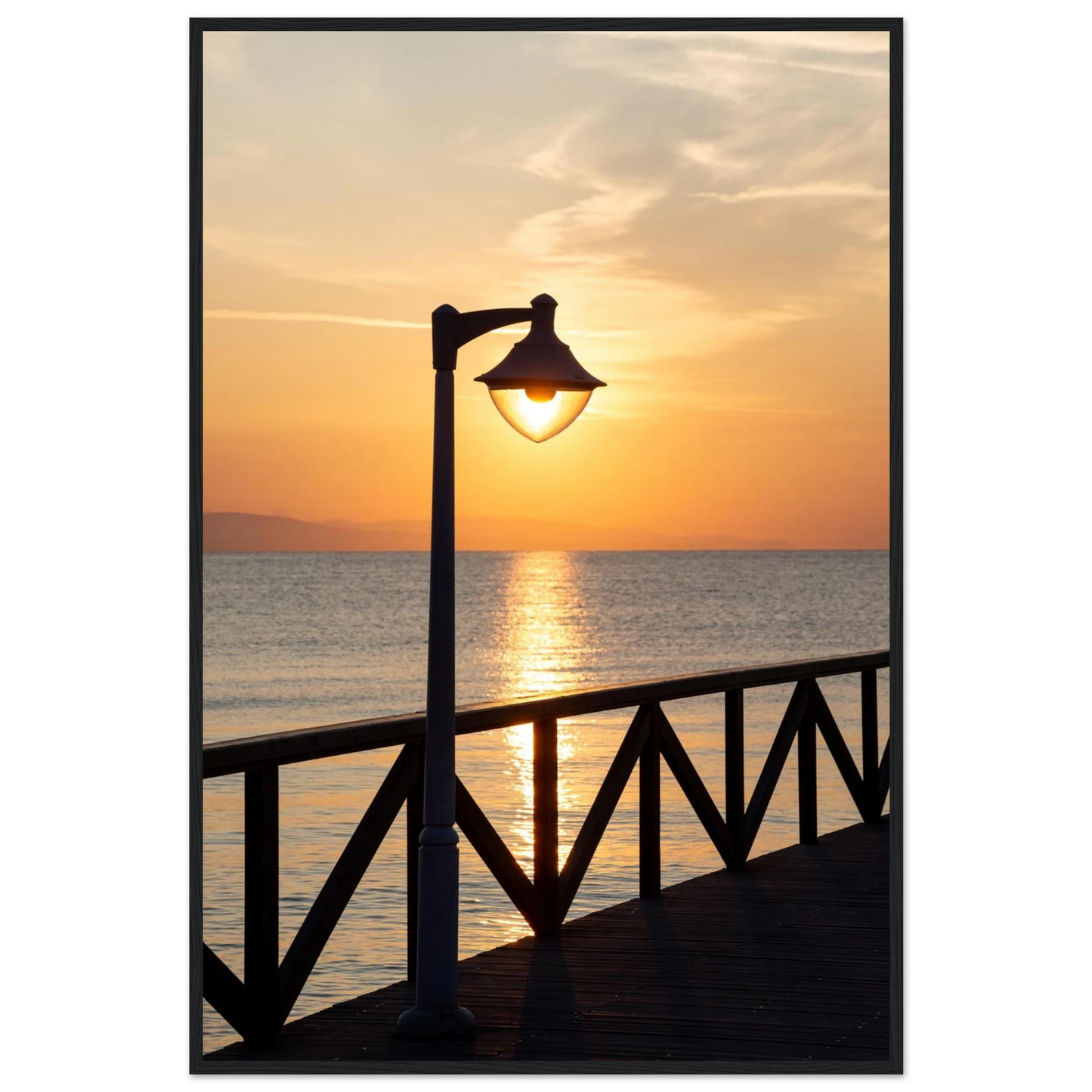 Wooden framed wall art of a sunset over the sea with a street lamp on the pier