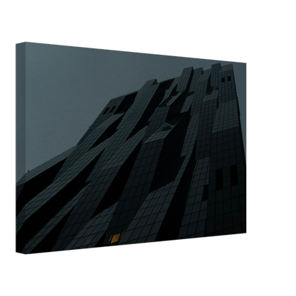 Bluish low angle view of a modern skyscraper with bold geometric lines and dark textured facade on Canvas Print wall art