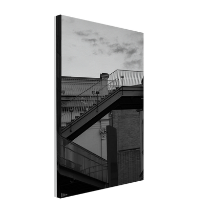 Black and white photo on a Canvas Print wall art of an outdoor staircase connecting two buildings under a dramatic cloudy sky