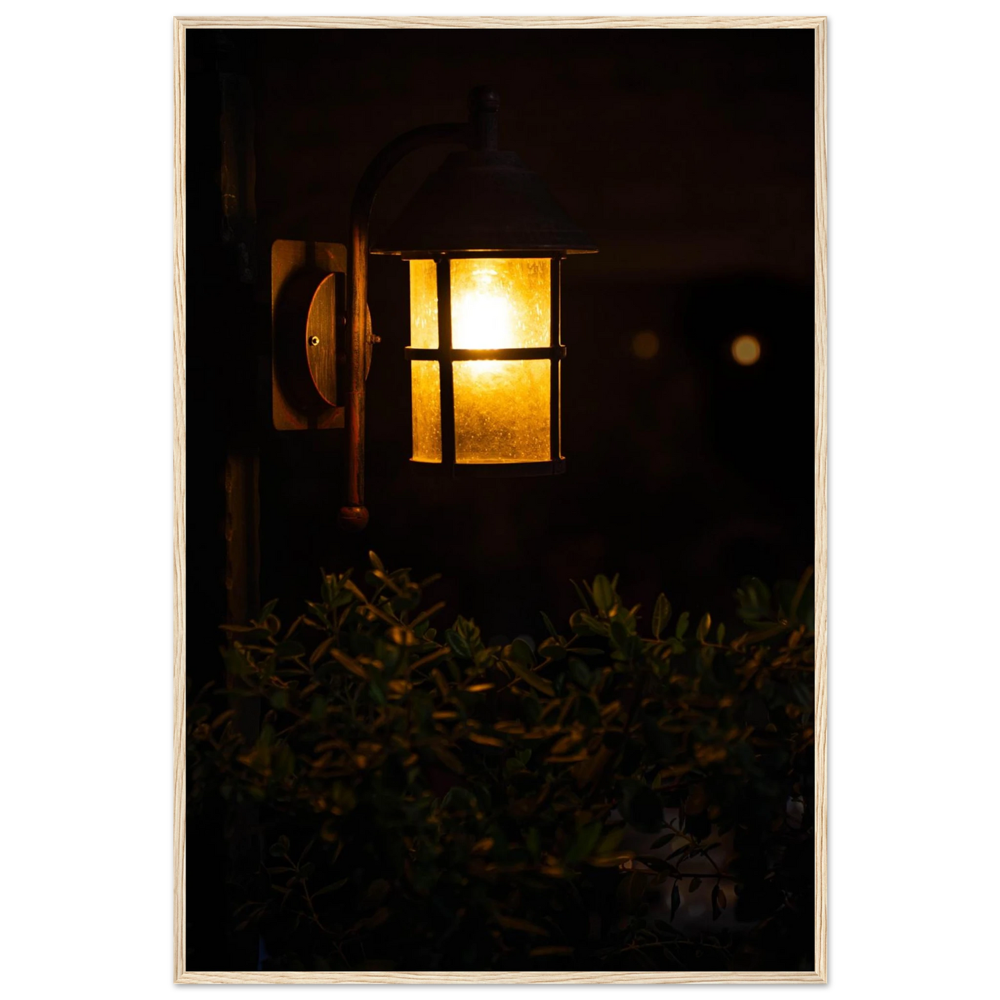 Glowing vintage lantern mounted on a wooden pole in front of a bush at night on wooden framed wall art
