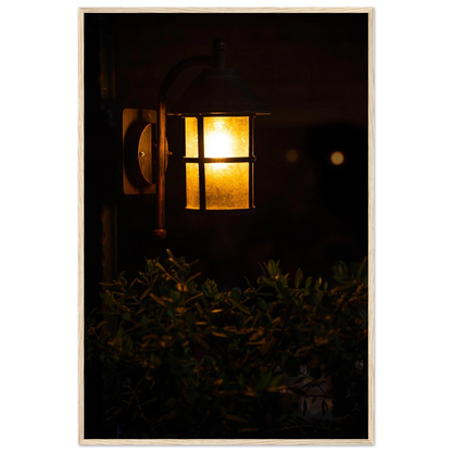 Glowing vintage lantern mounted on a wooden pole in front of a bush at night on wooden framed wall art