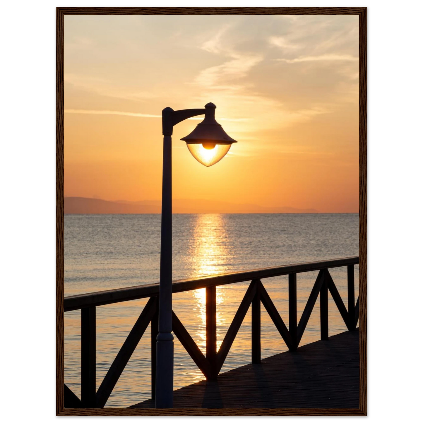 Wooden framed wall art of a sunset over the sea with a street lamp on the pier