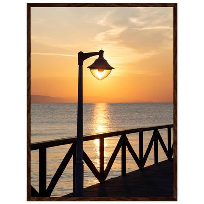 Wooden framed wall art of a sunset over the sea with a street lamp on the pier
