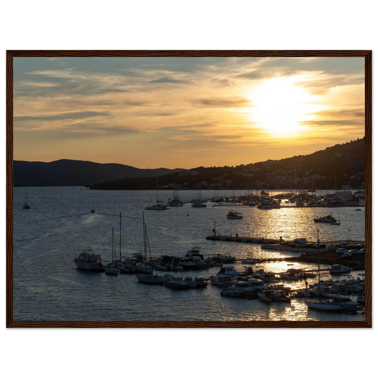 Wooden framed wall art of small boats anchored in a seaside port during Sunset at the harbor