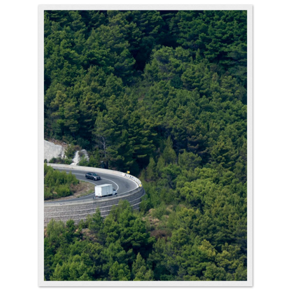 Aerial view of a winding road curve with cars surrounded by lush green forest landscape on wooden framed wall art