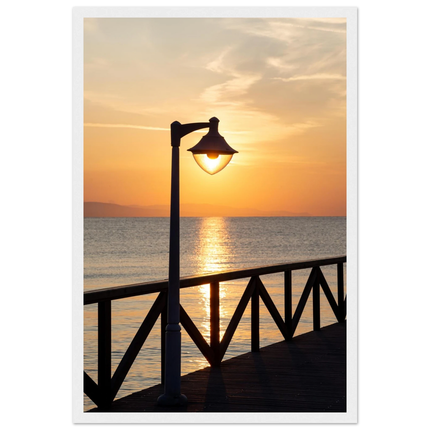 Wooden framed wall art of a sunset over the sea with a street lamp on the pier