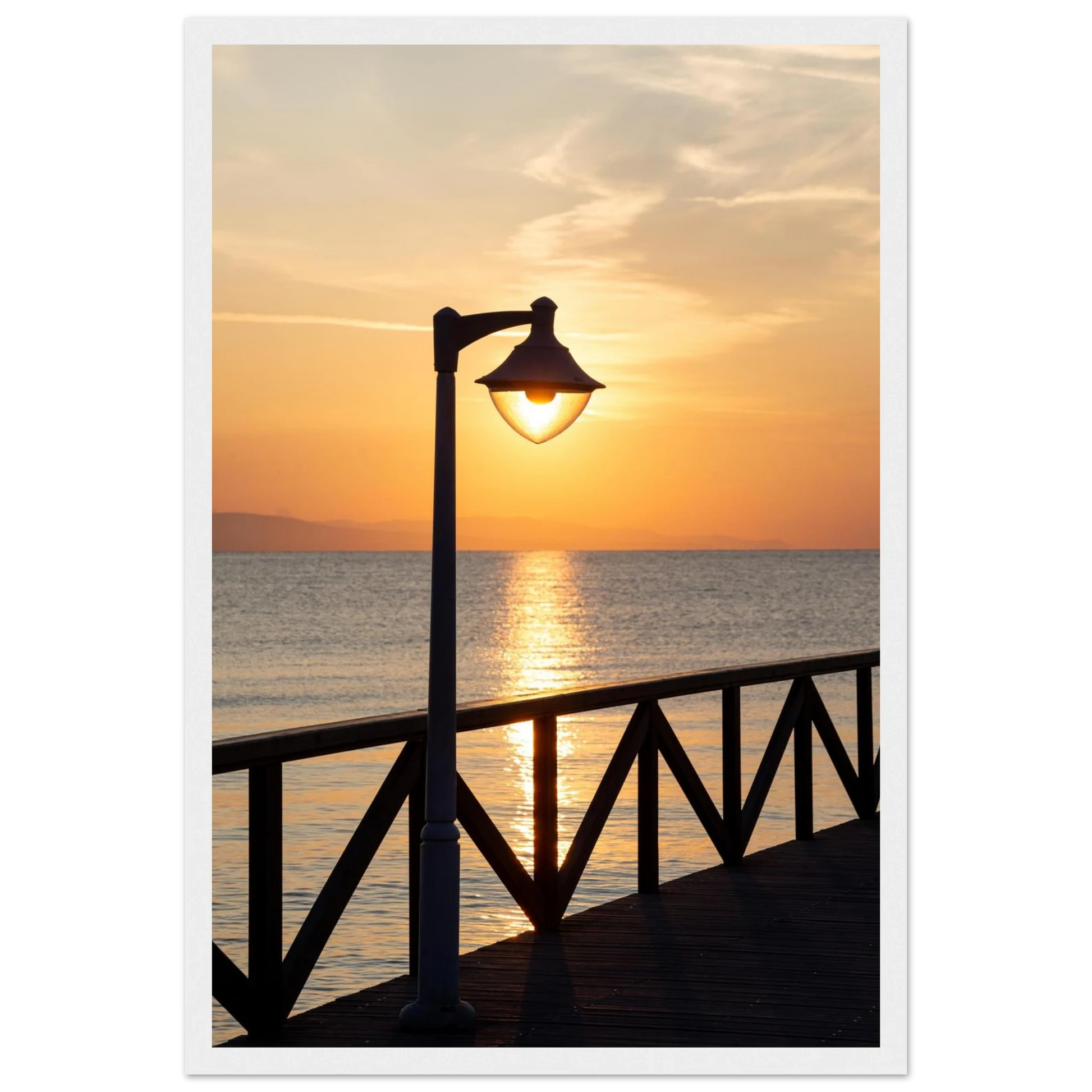Wooden framed wall art of a sunset over the sea with a street lamp on the pier