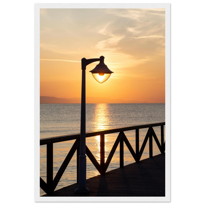 Wooden framed wall art of a sunset over the sea with a street lamp on the pier
