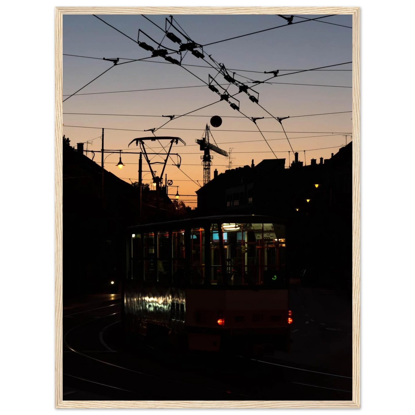 Wooden framed wall art featuring a tram the Nightline driving between houses under power lines during a golden sunset