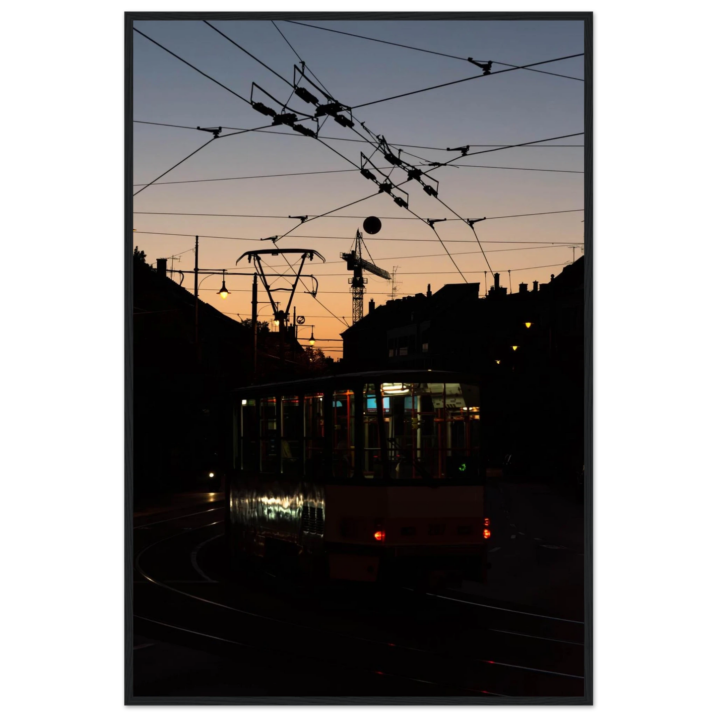 Wooden framed wall art featuring a tram the Nightline driving between houses under power lines during a golden sunset