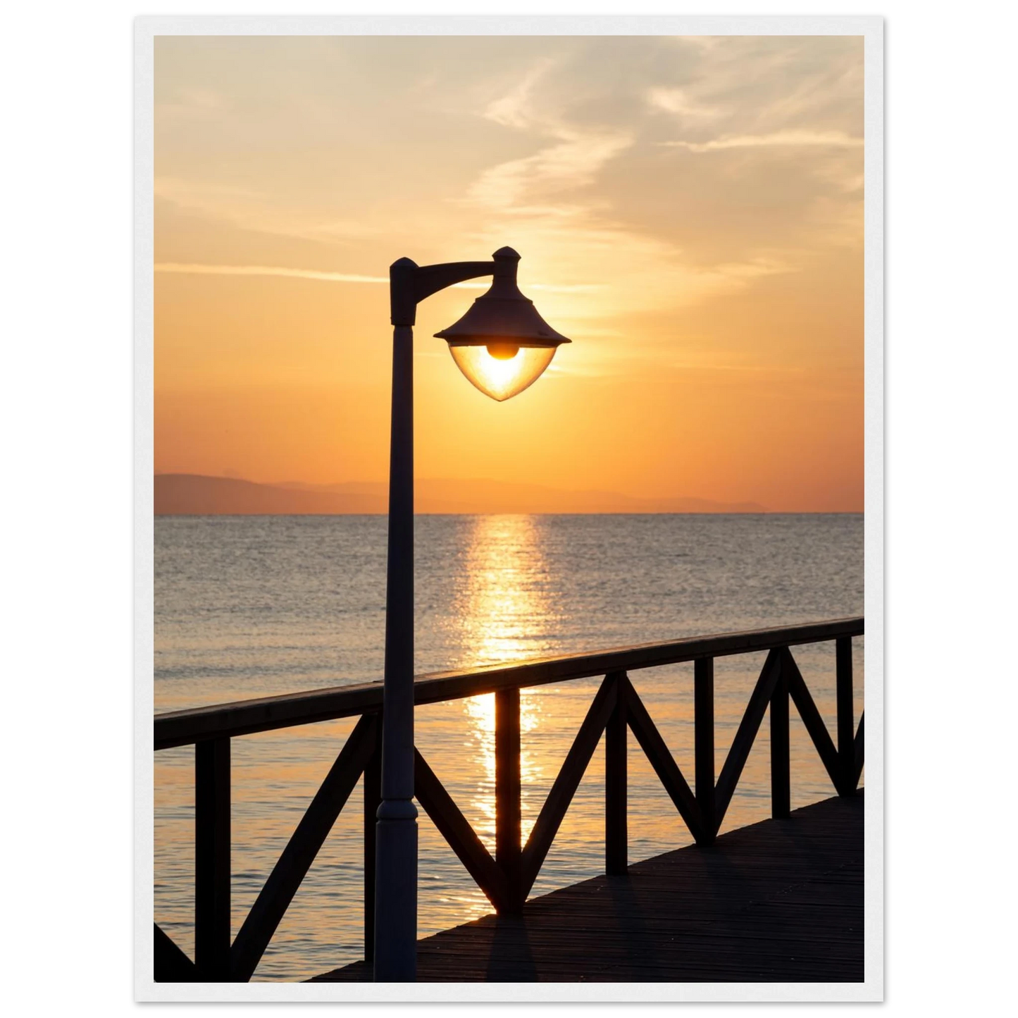 Wooden framed wall art of a sunset over the sea with a street lamp on the pier