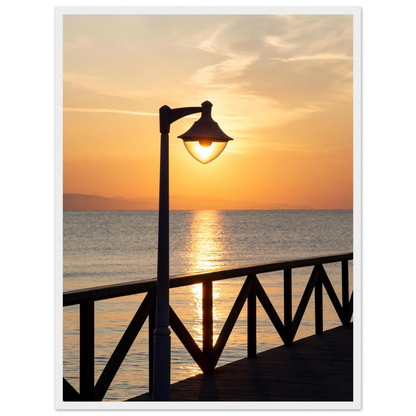 Wooden framed wall art of a sunset over the sea with a street lamp on the pier