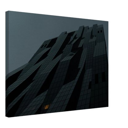 Bluish low angle view of a modern skyscraper with bold geometric lines and dark textured facade on Canvas Print wall art