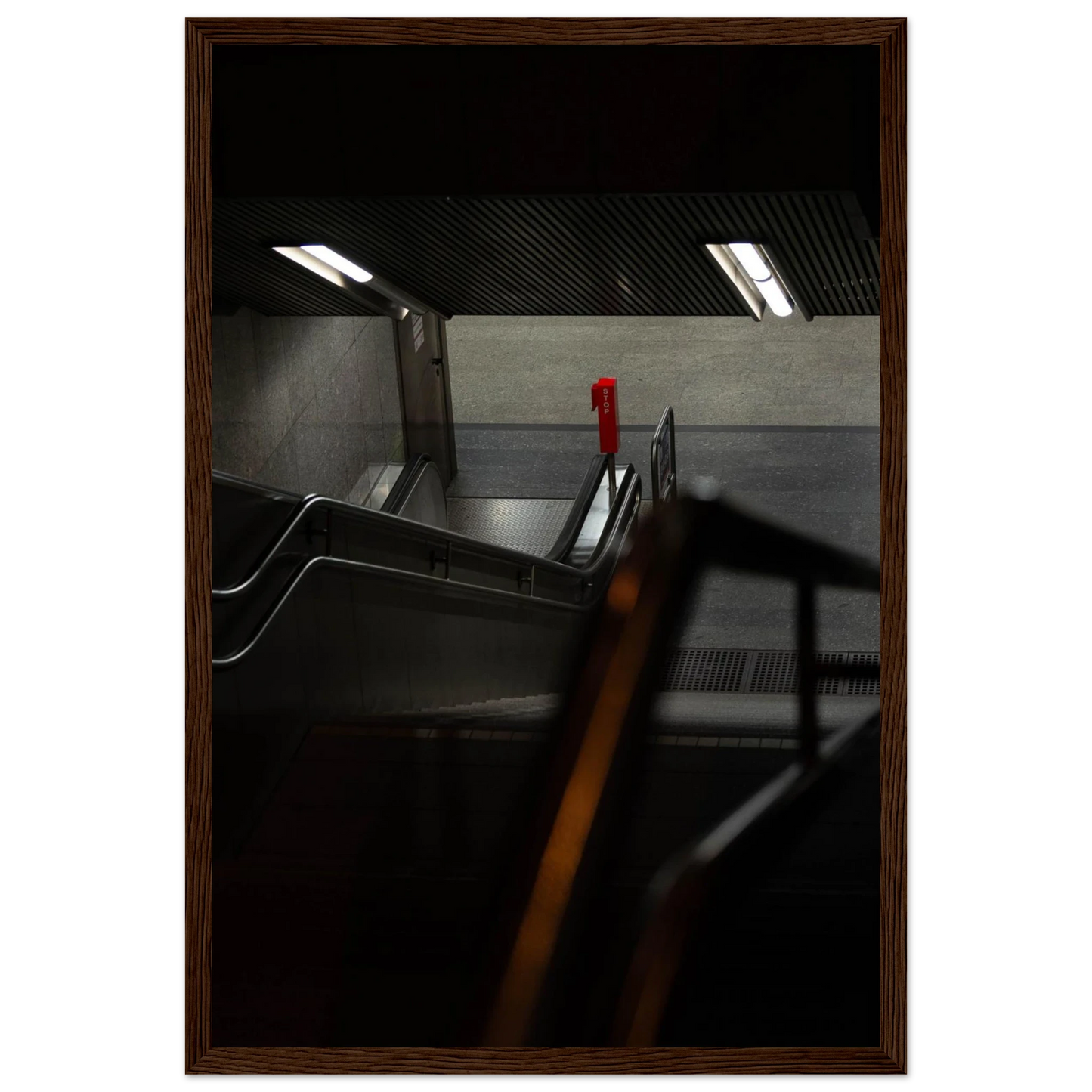 Nighttime view of a metro station entrance with illuminated signs and dark urban surroundings on wooden framed wall art