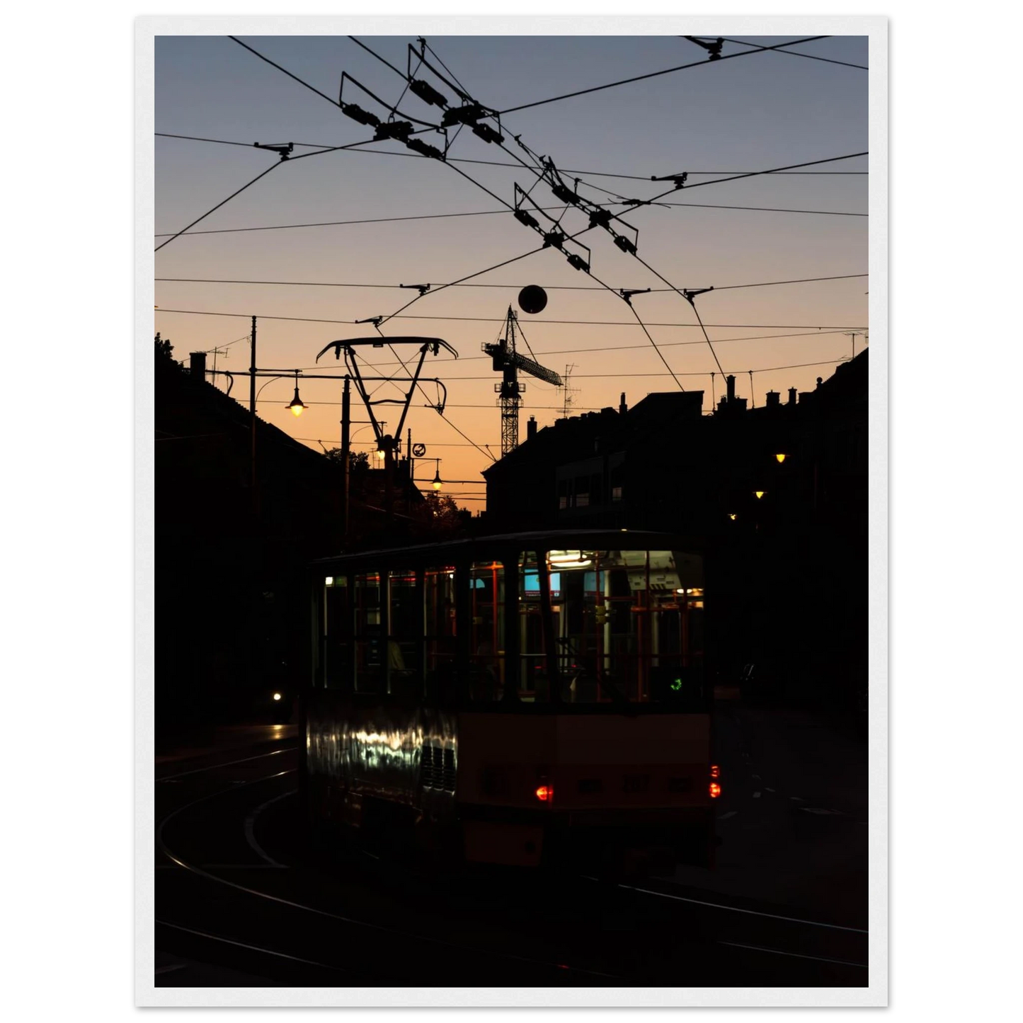 Wooden framed wall art featuring a tram the Nightline driving between houses under power lines during a golden sunset