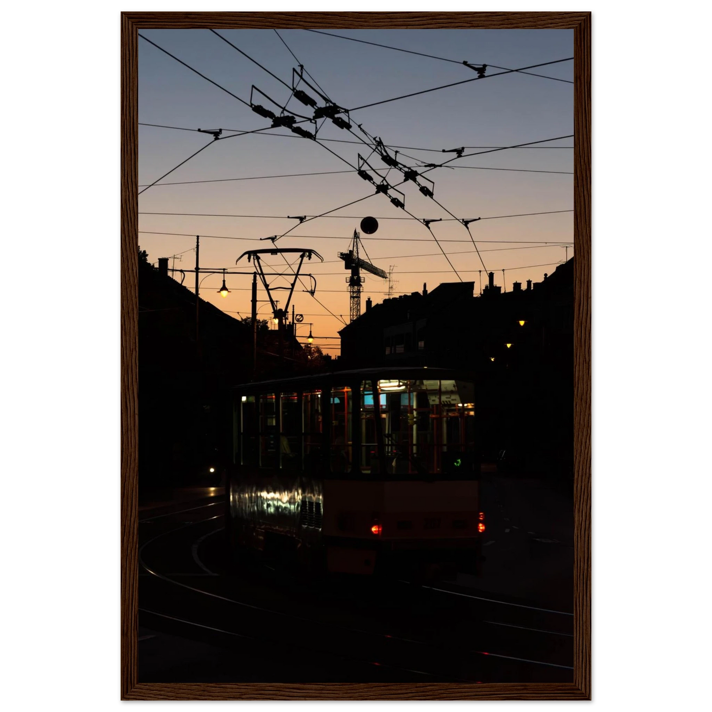 Wooden framed wall art featuring a tram the Nightline driving between houses under power lines during a golden sunset