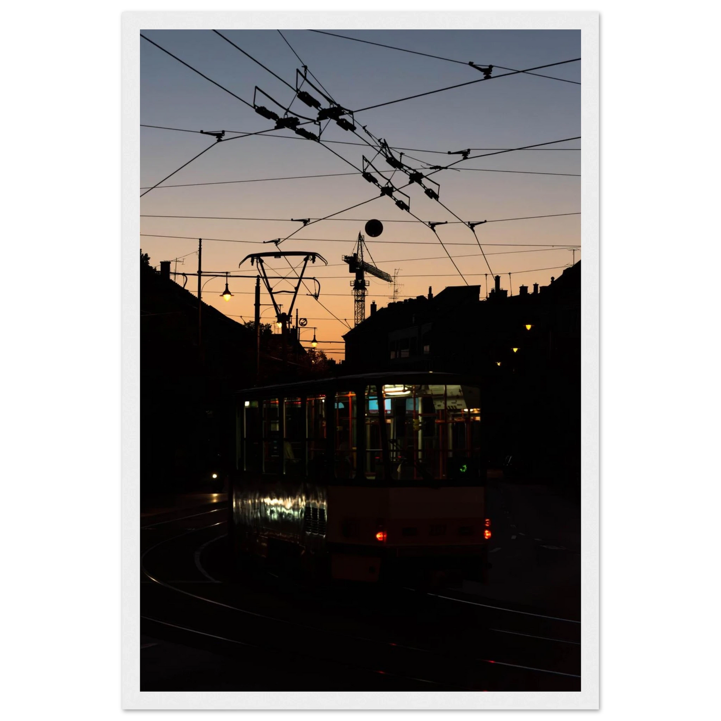 Wooden framed wall art featuring a tram the Nightline driving between houses under power lines during a golden sunset