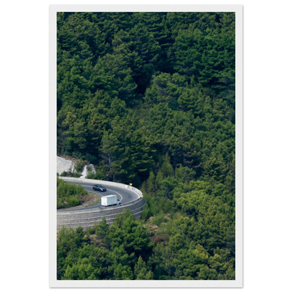 Aerial view of a winding road curve with cars surrounded by lush green forest landscape on wooden framed wall art