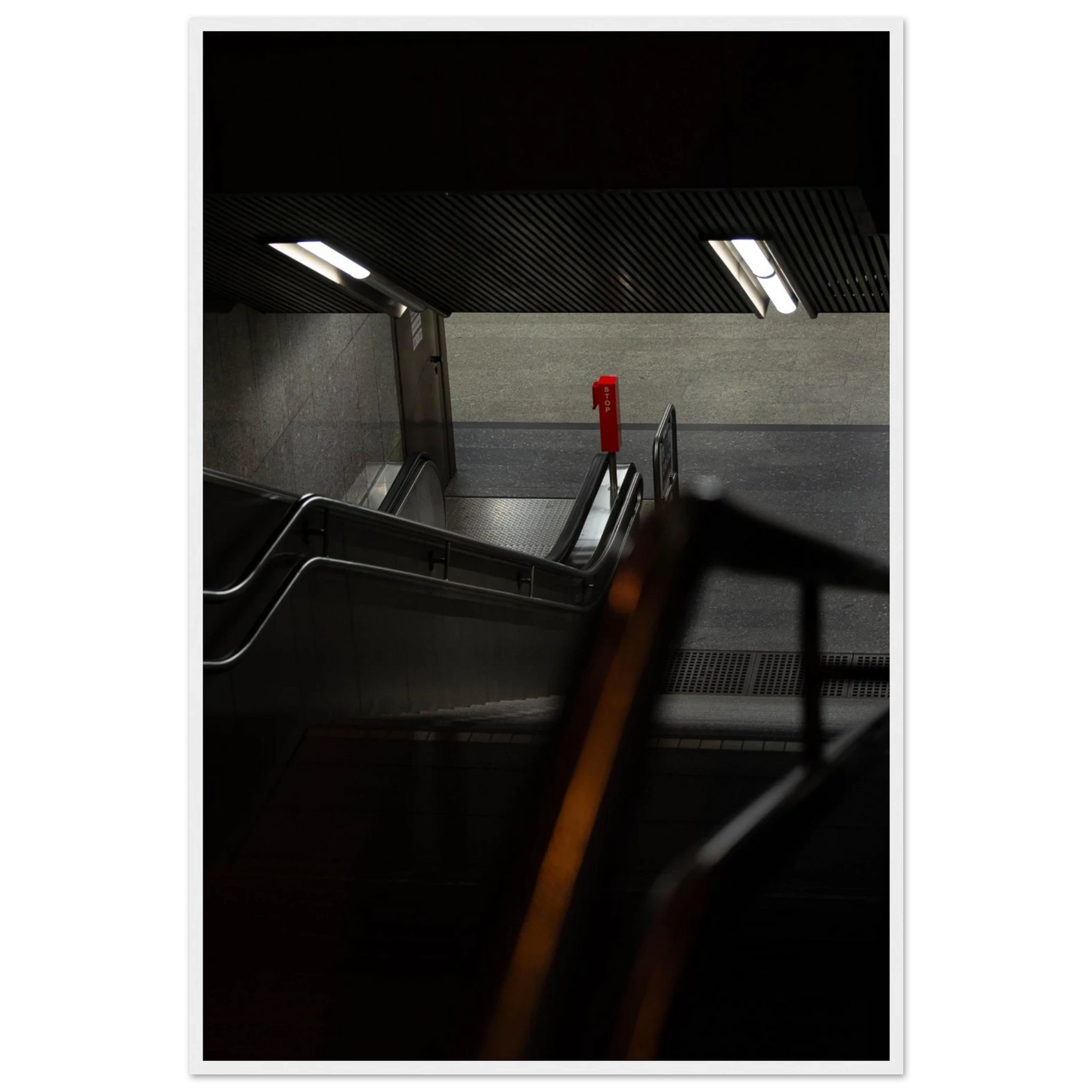 Nighttime view of a metro station entrance with illuminated signs and dark urban surroundings on wooden framed wall art