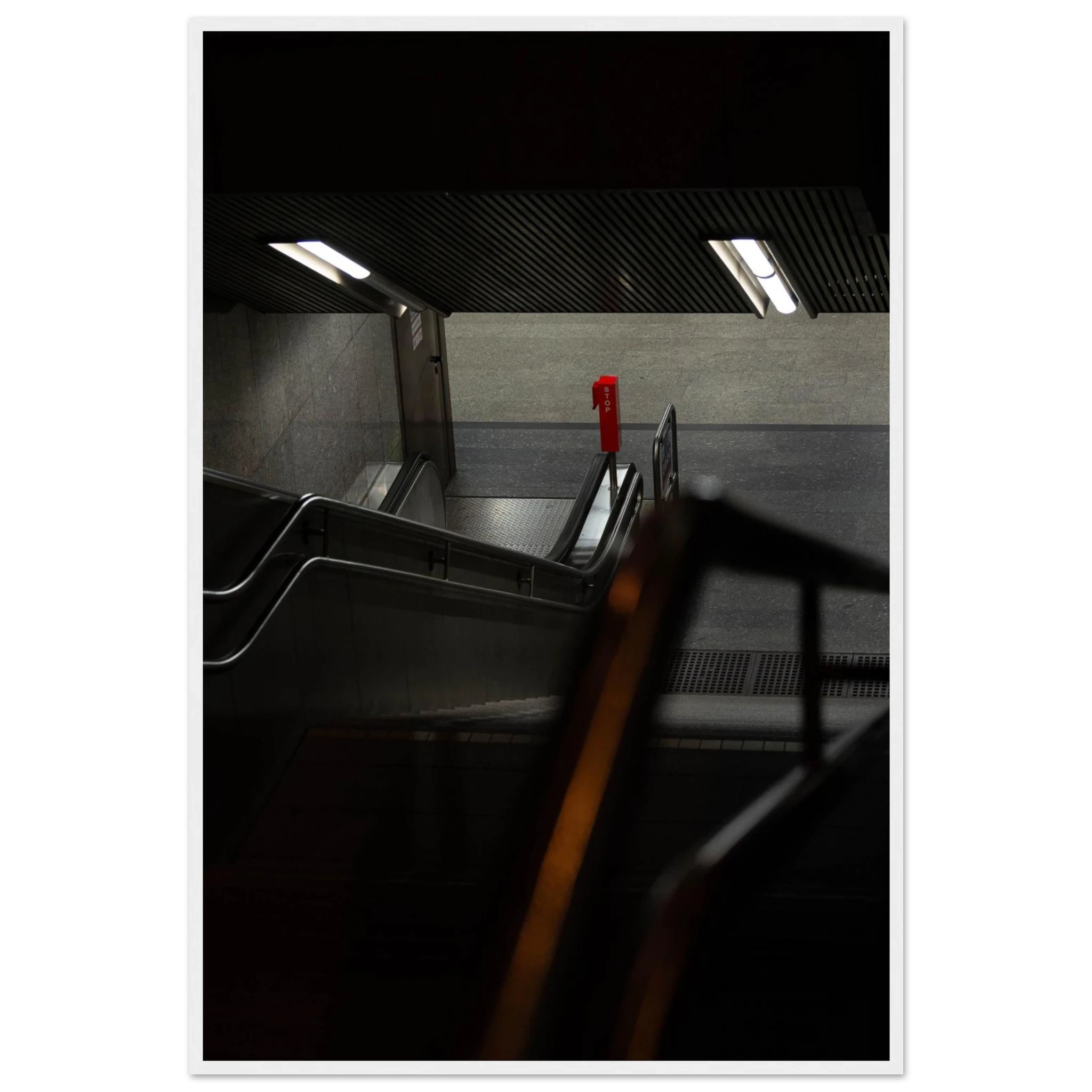 Nighttime view of a metro station entrance with illuminated signs and dark urban surroundings on wooden framed wall art