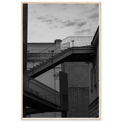 Black and white photo on a wooden frame wall art of an outdoor staircase connecting two buildings under a dramatic cloudy sky