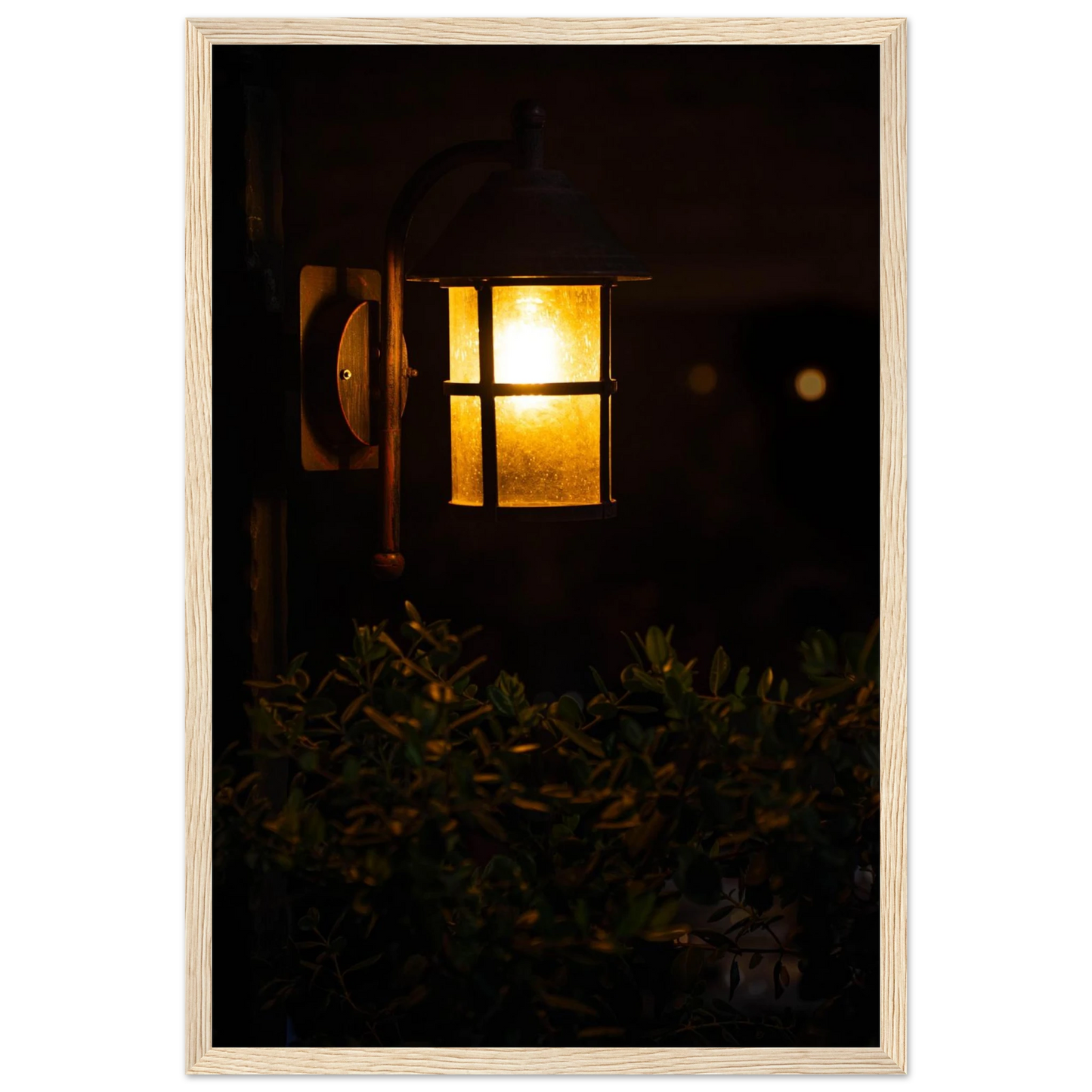 Glowing vintage lantern mounted on a wooden pole in front of a bush at night on wooden framed wall art
