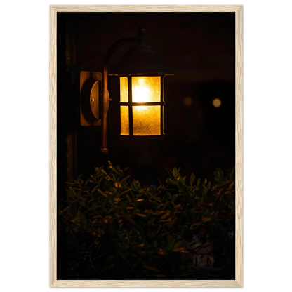 Glowing vintage lantern mounted on a wooden pole in front of a bush at night on wooden framed wall art