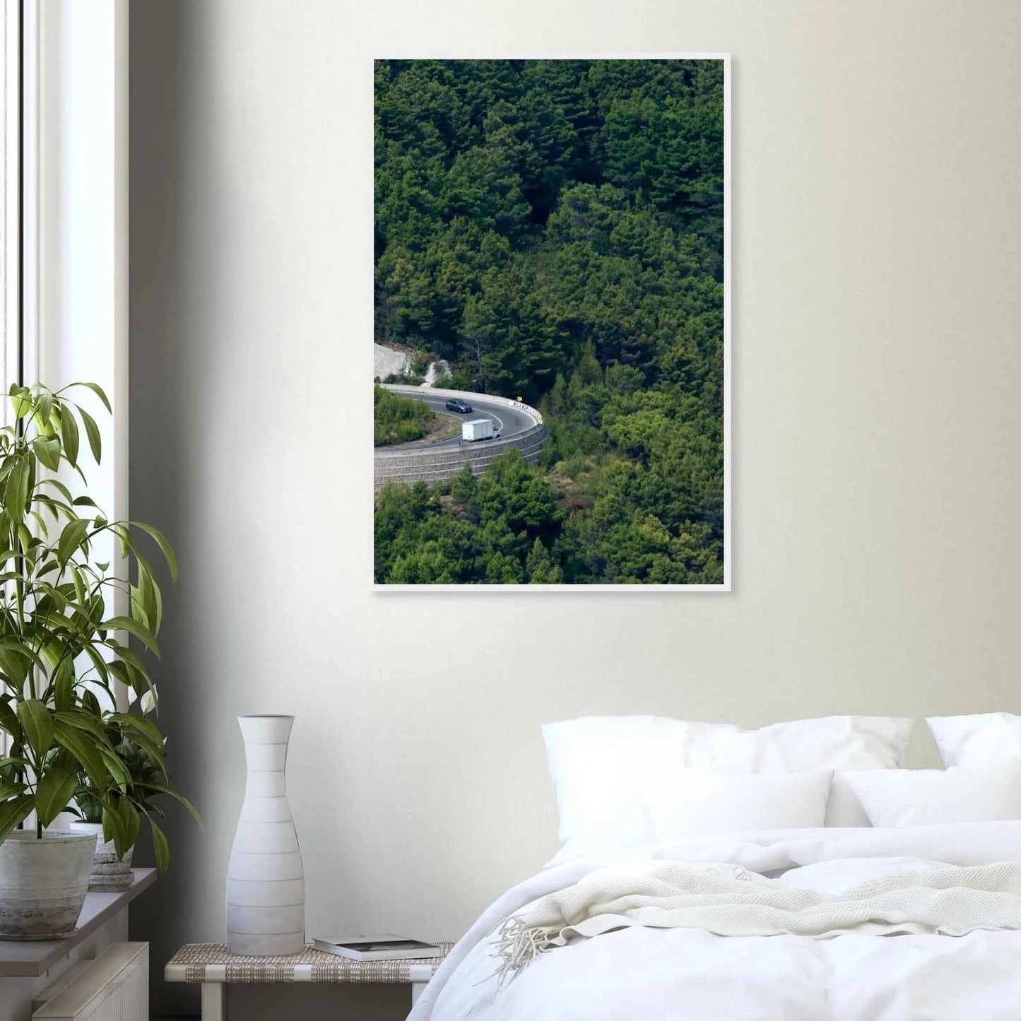 Aerial view of a winding road curve with cars surrounded by lush green forest landscape on wooden framed wall art on the wall in the Bedroom